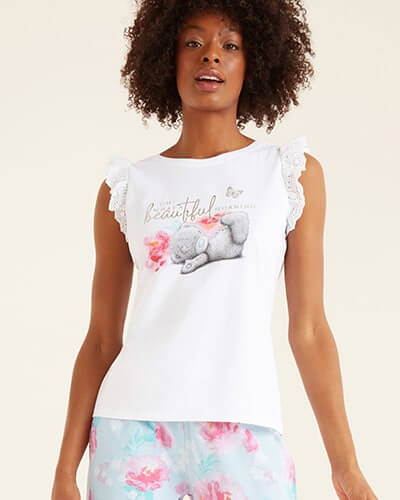 White PJ vest with broderie trim on the sleeves, 'oh what a beautiful morning' written across the chest with a Tatty Teddy drawing. Paired with blue PJ bottoms with pink flowers