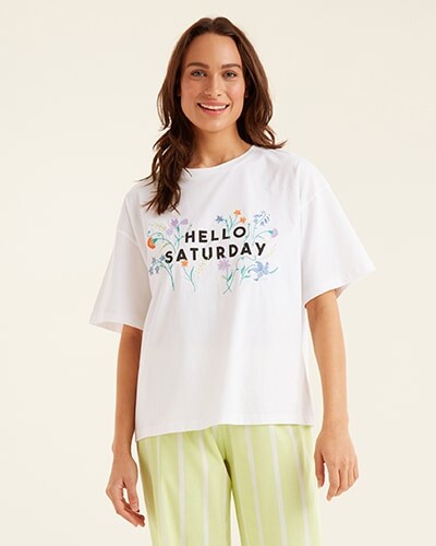Loose white short sleeve T-shirt with 'Hello Saturday' written across the chest, with flowers framing it. Paired with light yellow and white striped PJ bottoms