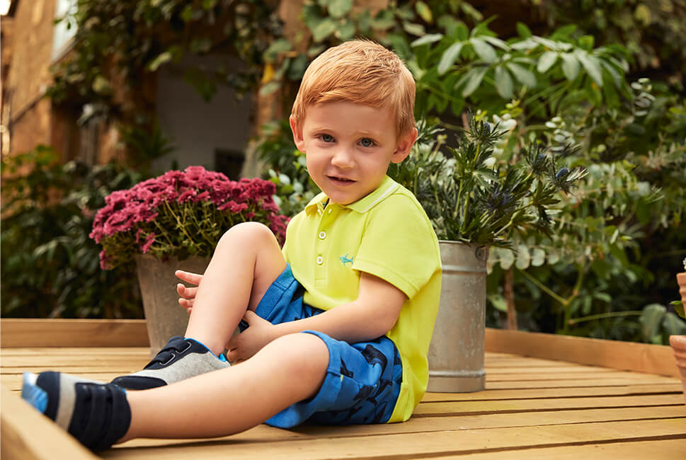 Lime polo with small shark embroided on the chest. Blue shorts with black shark pattern