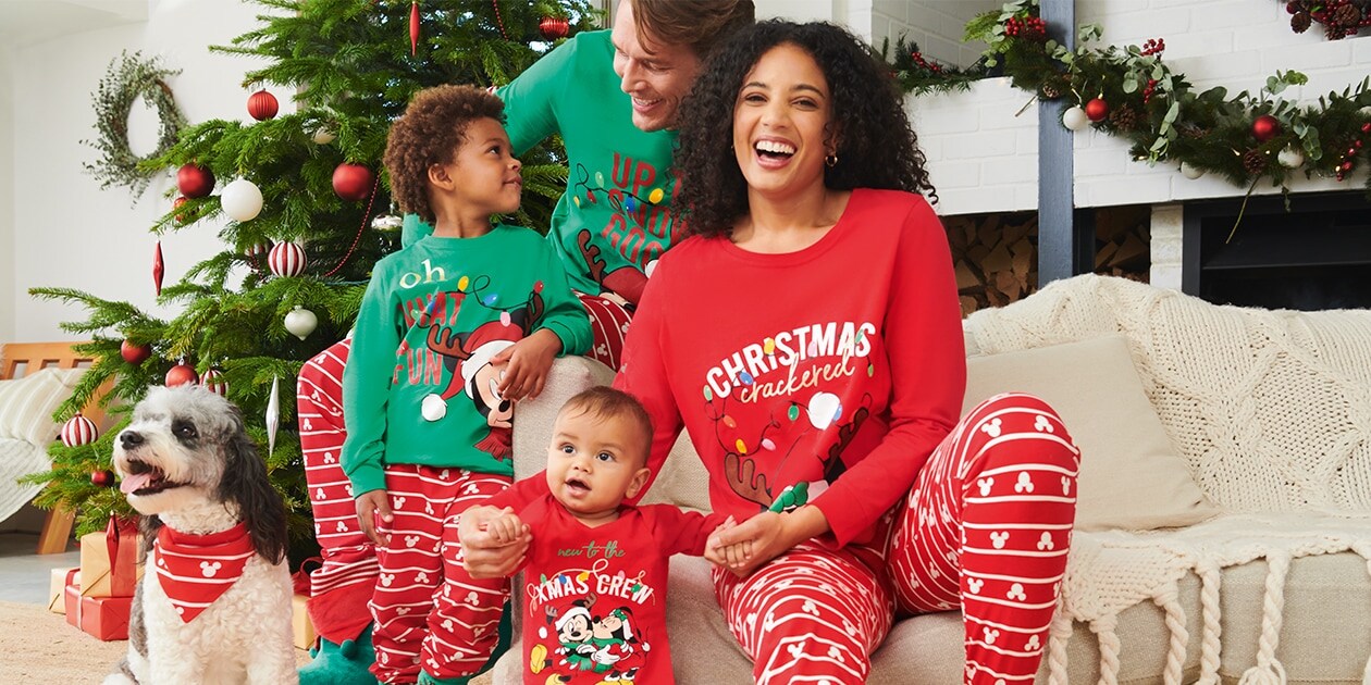   Adult Christmas pyjama sets in red bottoms with a Mickey Mouse print and green or red long-sleeved top with festive Mickey Mouse image. Kids' set in red bottoms with Mickey print and green long-sleeved top with festive Mickey image. Baby set in red bottoms with Mickey print and red sleeve top with festive Mickey and Minnie image. Dog handkerchief in red with Mickey print.