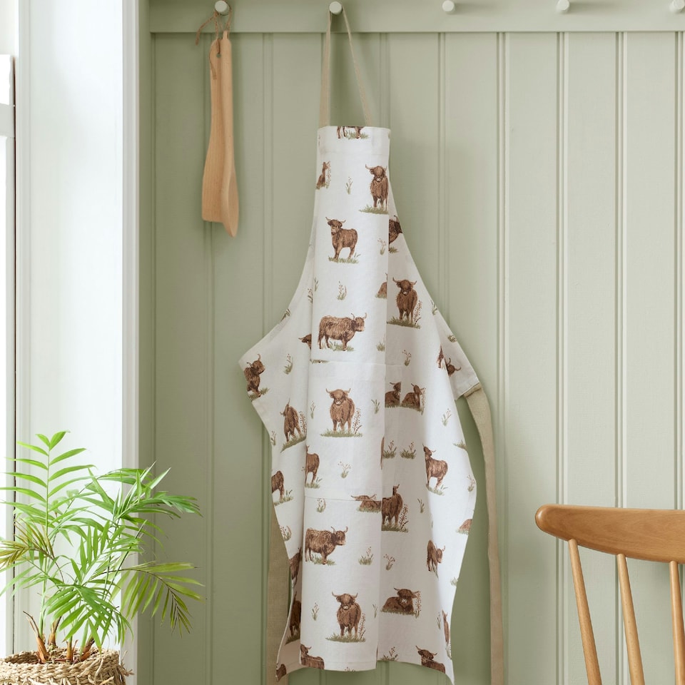 image 1 of Catherine Lansfield Angus Highland Cow Cotton Kitchen Adult Apron Natural Cream | Natural