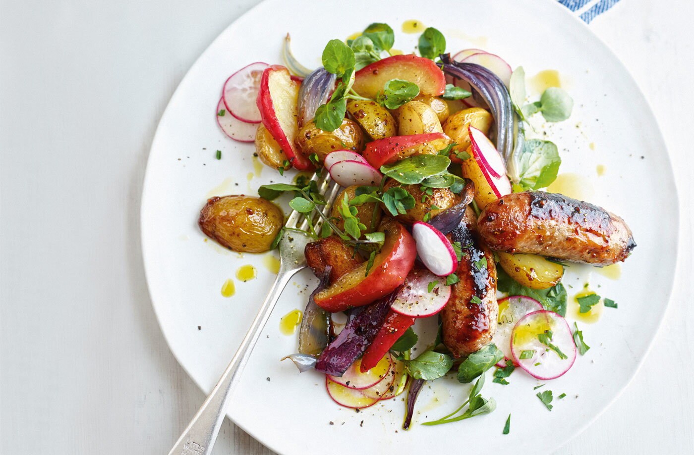 Sticky sausages, apples and potatoes with radish salad