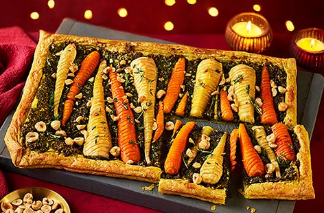 Image of "Hasselback honey parsnip and carrot puff pastry tart with winter pesto"