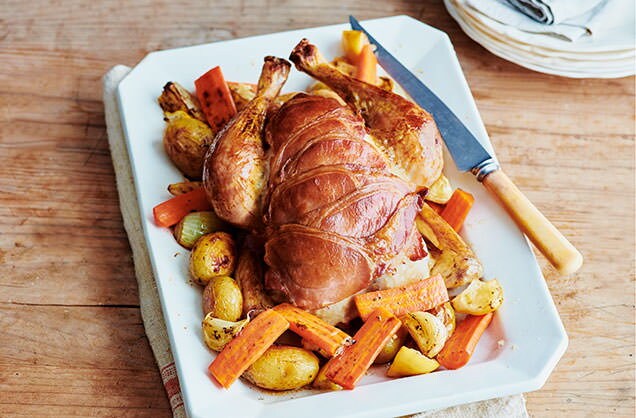 Bacon-wrapped roast chicken with lemons and potatoes