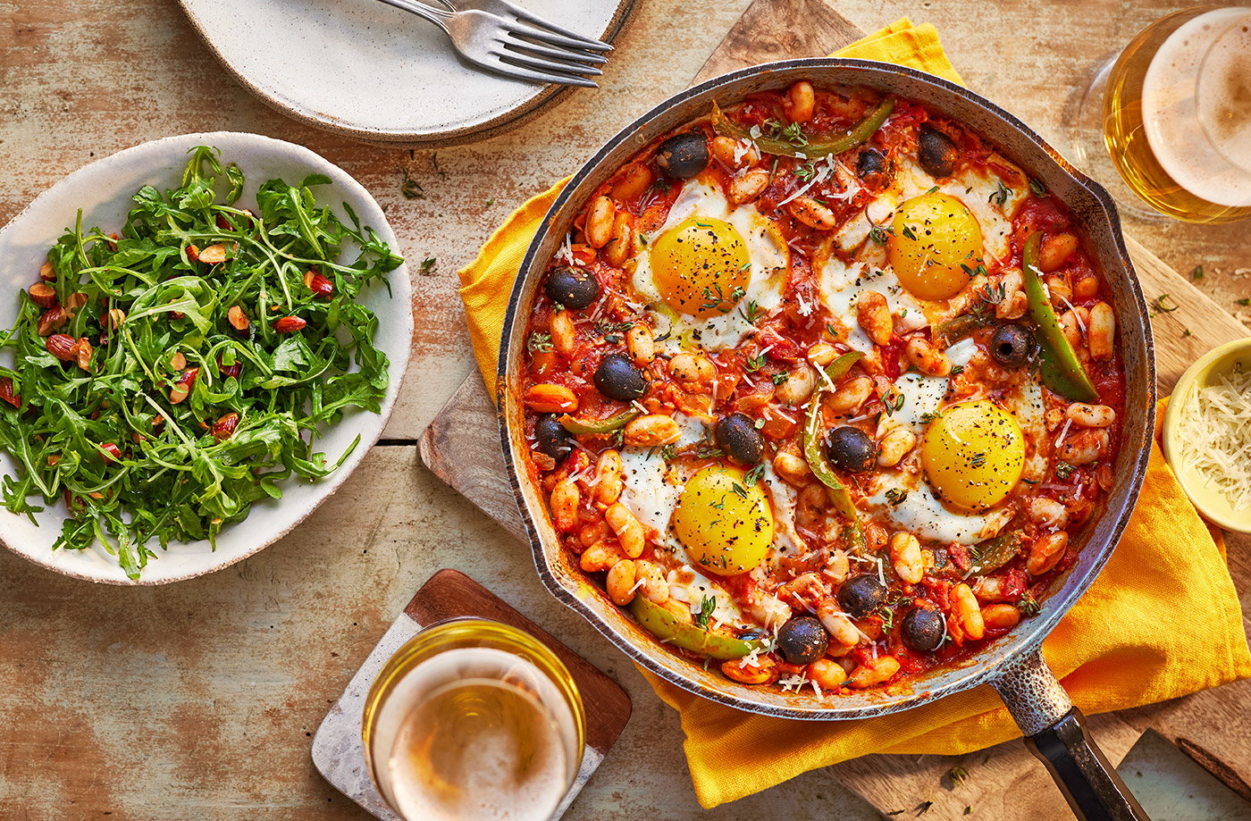 Baked eggs and Manchego with rocket and almond salad​