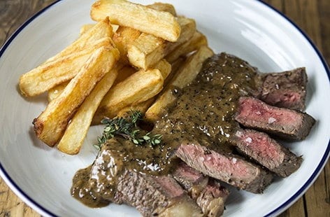 Image of "Ribeye steak and peppercorn sauce with chips"