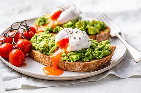 Image of "Smashed avocado on toast with poached eggs and tomatoes"