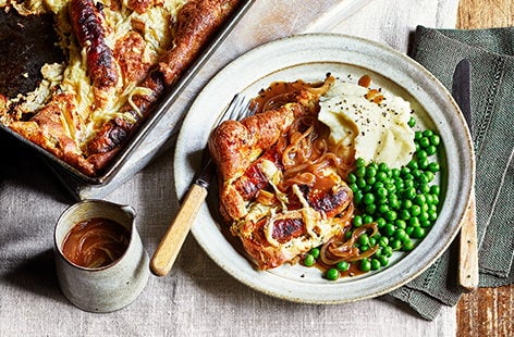 Image of "Cheese and onion toad-in-the-hole with mash, peas and gravy"