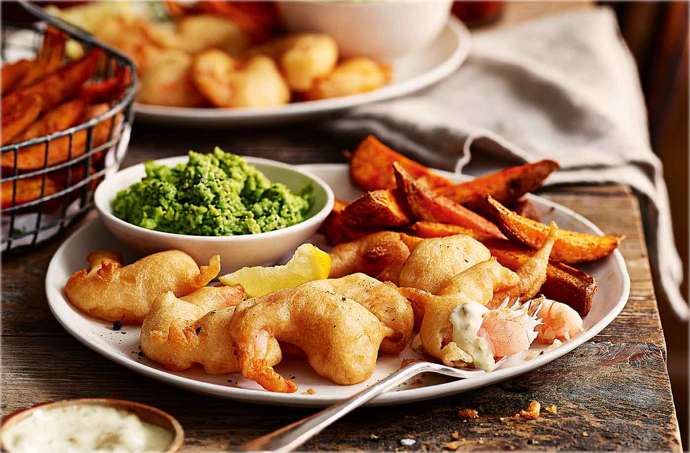 Beer-battered scampi with sweet potato chips and mushy peas