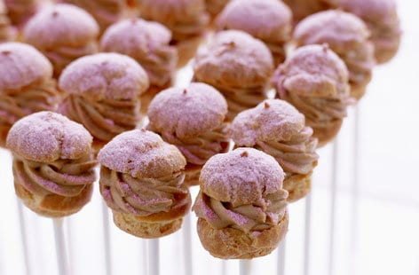 Image of "Mini hazelnut choux buns coated in pink icing sugar"